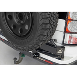 Terrafirma swing away spare tire carrier for LR3 and LR4 with black powder-coated finish, gas strut assist, and stainless steel latch